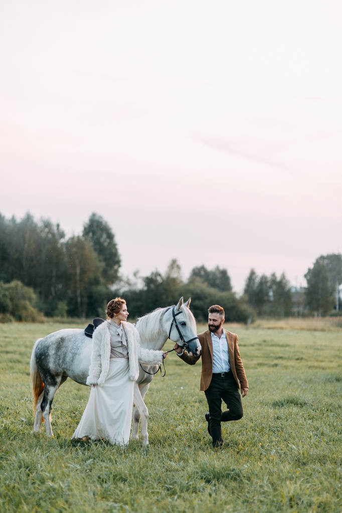 Mariage à l'américaine, sur un ranch avec un cheval. Promenez-vous en couple dans les champs au coucher du soleil, entre amis et à cheval. Couple moderne et idées pour la cérémonie
. - Photo, image