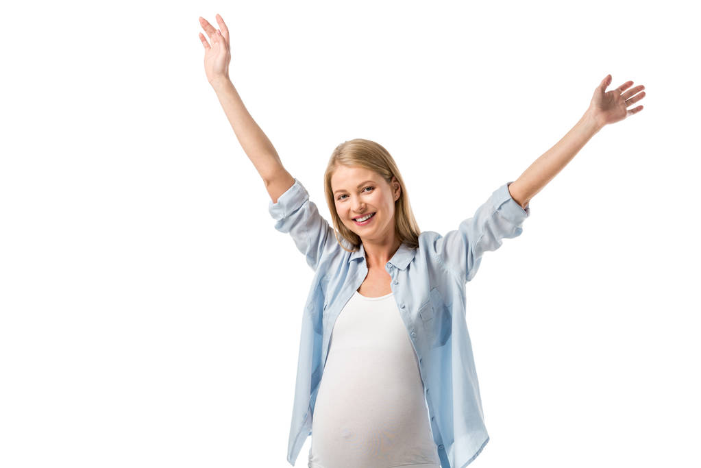szczęśliwy piękna kobieta w ciąży z uniesionymi rękoma patrząc na kamery na białym tle - Zdjęcie, obraz