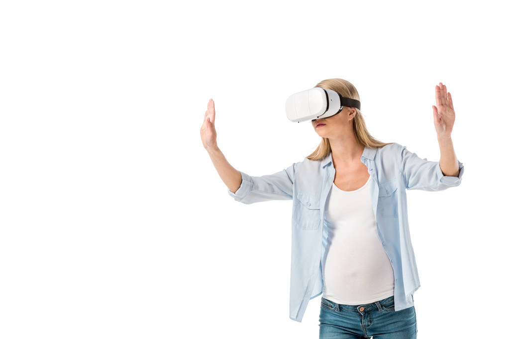 ausdrucksstarke schwangere Frau in Virtual-Reality-Headset gestikuliert mit Händen isoliert auf weiß - Foto, Bild