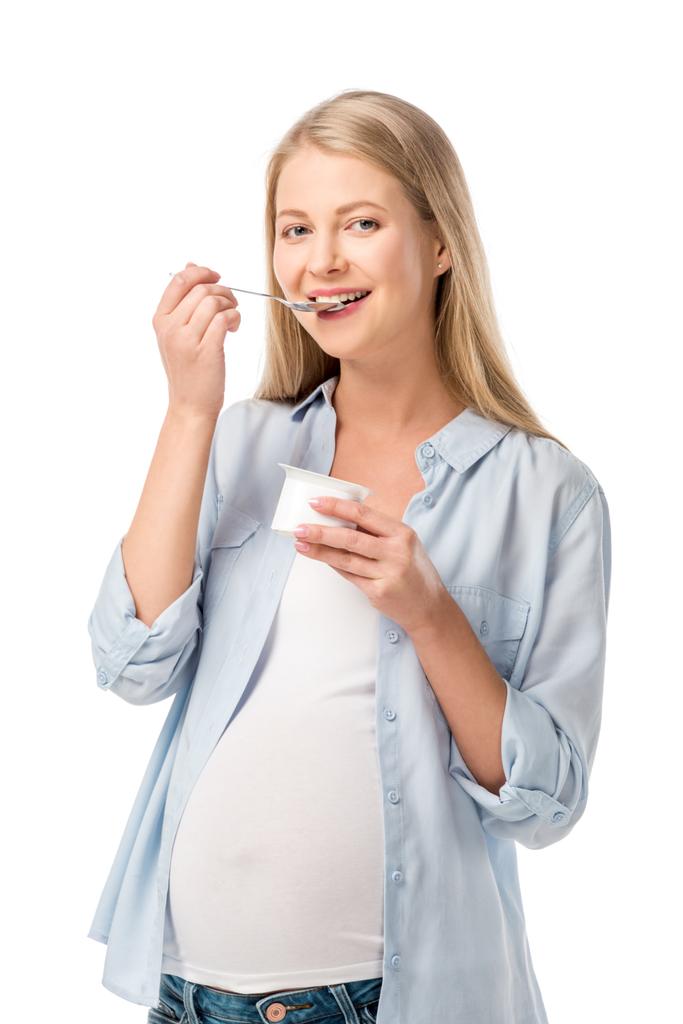 χαμογελώντας έγκυος γυναίκα τρώει γιαούρτι με κουτάλι που απομονώνονται σε λευκό - Φωτογραφία, εικόνα