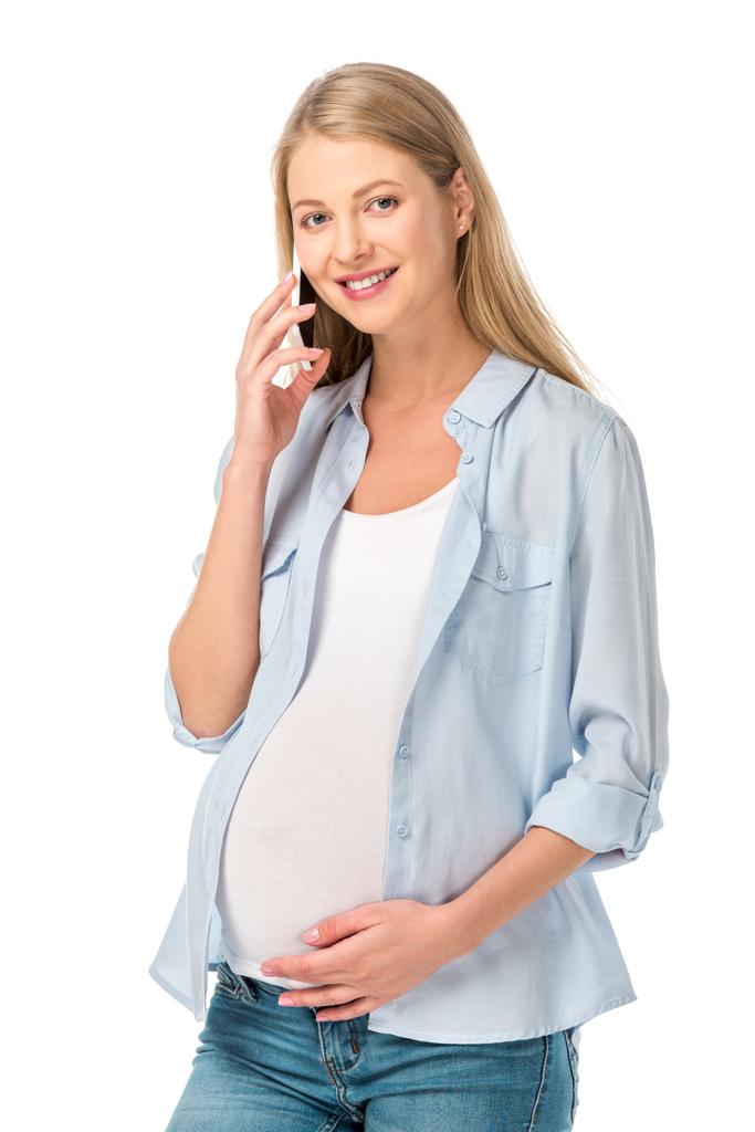 beautiful pregnant woman touching stomach and talking on smartphone isolated on white - Photo, Image