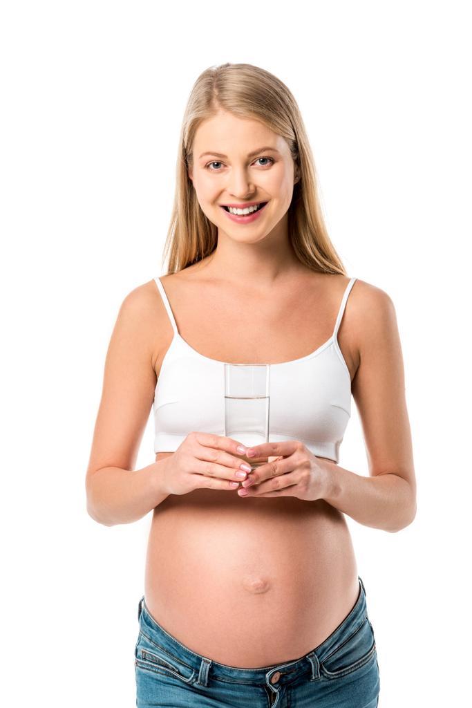 uśmiecha się kobieta w ciąży, trzymając szklankę czystej wody na białym tle - Zdjęcie, obraz