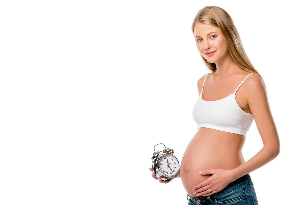 mujer embarazada rubia sosteniendo reloj despertador aislado en blanco
 - Foto, imagen