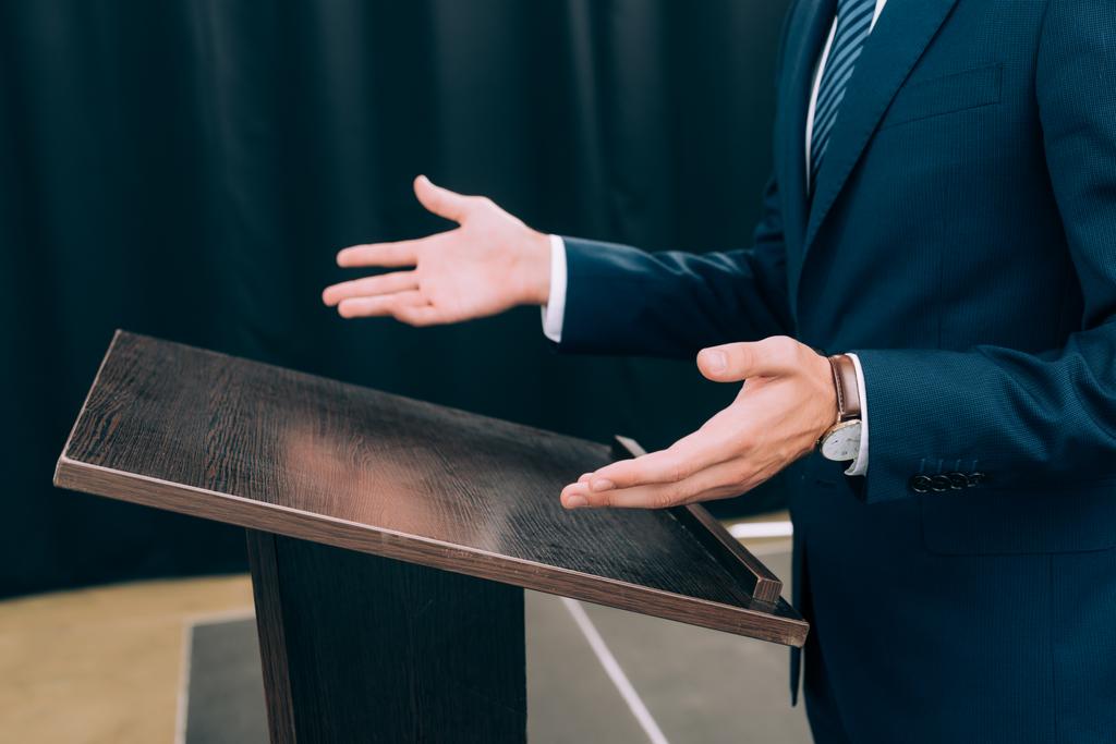 imagen recortada del profesor de pie y el gesto en el podio tribuna durante el seminario en la sala de conferencias
 - Foto, Imagen