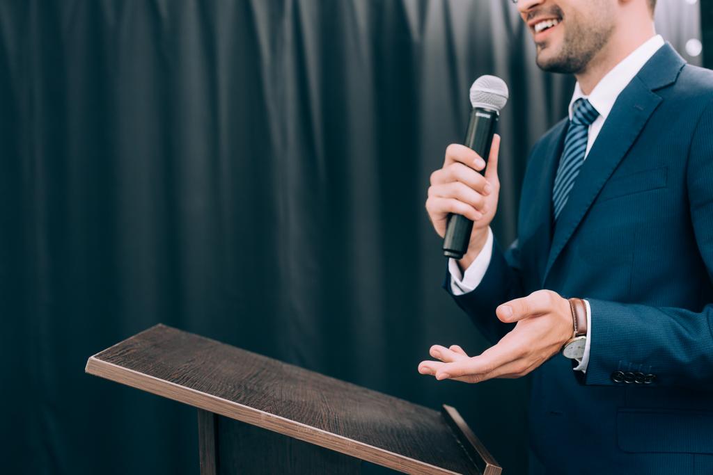 abgeschnittenes Bild des gestikulierenden und ins Mikrofon sprechenden Redners auf der Podiumstribüne während des Seminars im Konferenzsaal - Foto, Bild