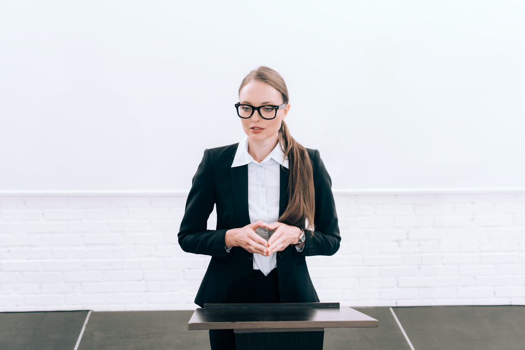 attraente docente in occhiali in piedi sul podio tribune durante il seminario in sala conferenze
 - Foto, immagini