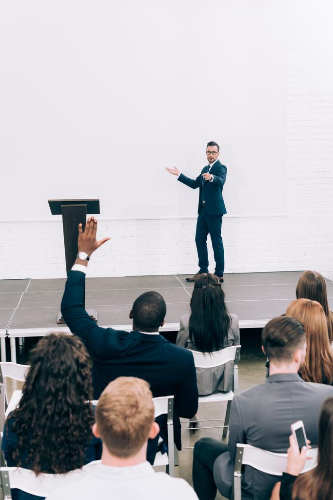 participante afroamericano levantando la mano, conferenciante hablando con el público durante la presentación en la sala de conferencias
 - Foto, Imagen