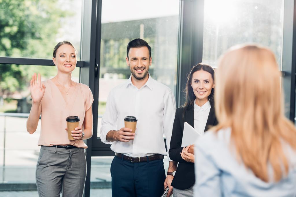 sorrindo colegas olhando para empresária durante coffee break no escritório
 - Foto, Imagem