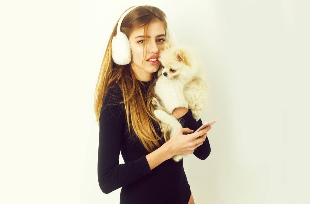 イヤーマフ ポメラニアン犬を押しながらスマート フォンを使用してのきれいな女の子 - 写真・画像
