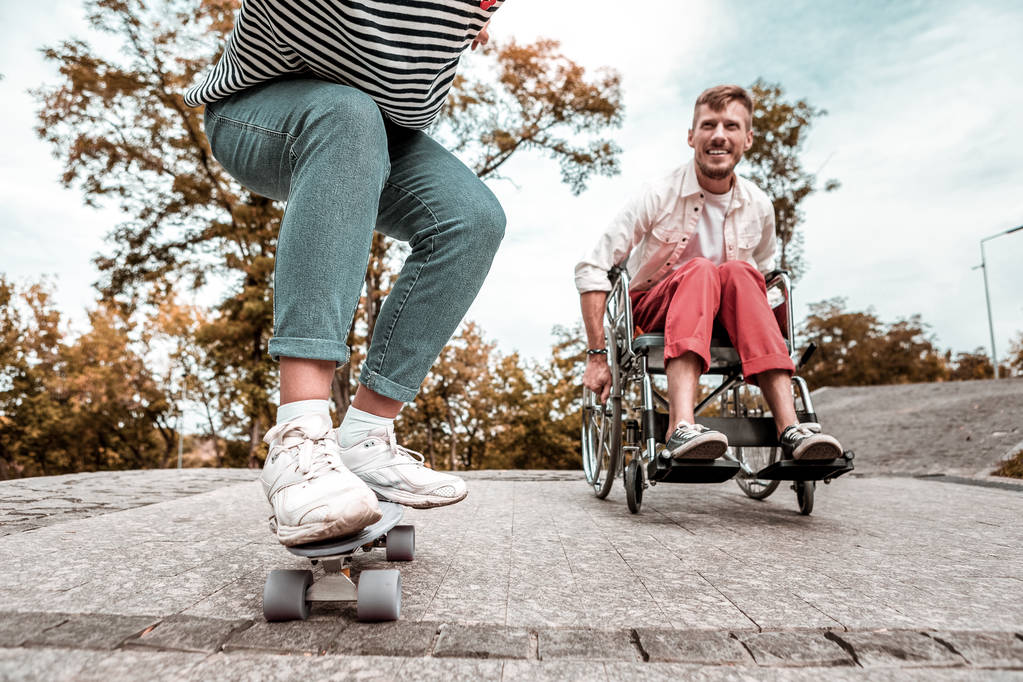 Hombre discapacitado activo compitiendo con su amigo y montando su silla de ruedas
 - Foto, Imagen