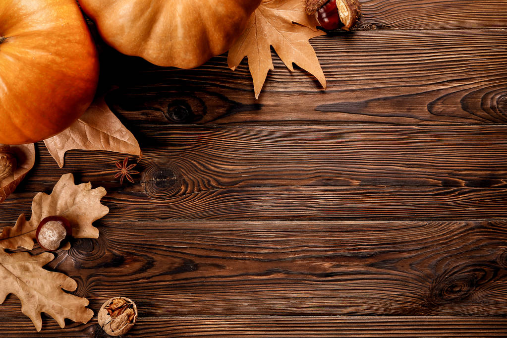 Thanksgiving background concept. Local produce pumpkin, chestnut, autumn dry oak & maple leaves and anise for decoration on wood textured table. Close up, copy space, top view, flat lay. - Photo, Image