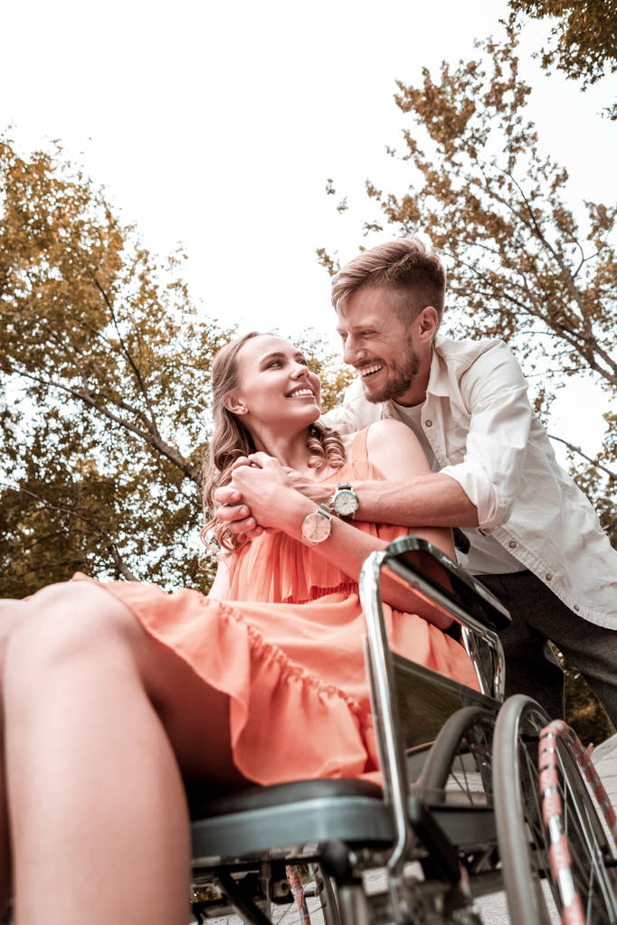 Positiivinen mies nauraa halatessaan rakas vammainen nainen
 - Valokuva, kuva