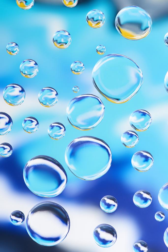 vista close-up de belas gotas de água transparentes no fundo abstrato azul
 - Fotografia, imagem