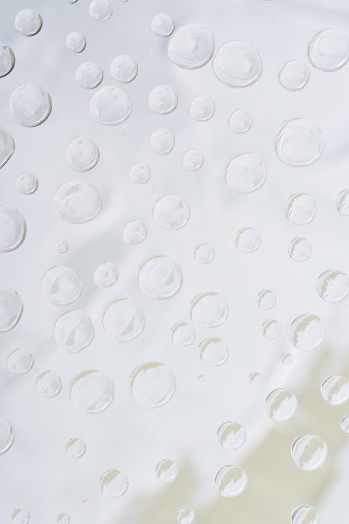 vergrote weergave van transparant water druppels op lichte abstracte achtergrond - Foto, afbeelding