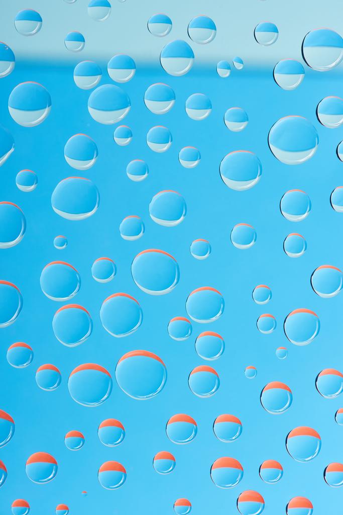 lähikuva läpinäkyvistä vesipisaroista kirkkaan sinisellä pohjalla
 - Valokuva, kuva