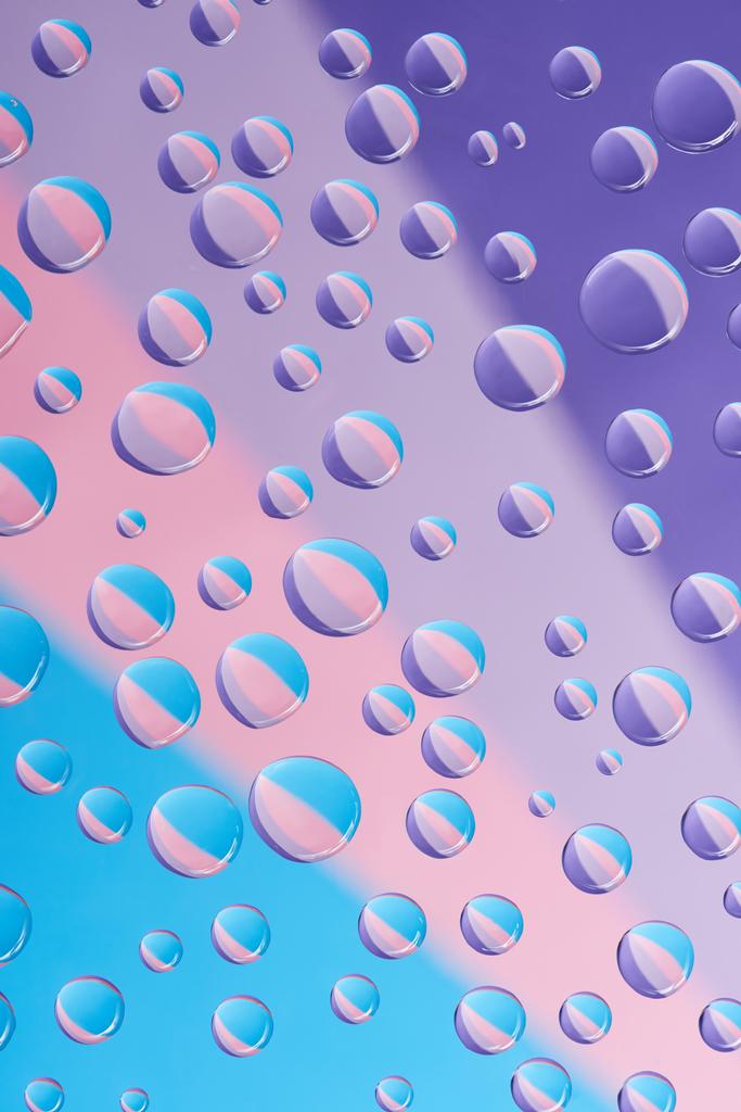 vista close-up de gotas de água transparentes em fundo colorido brilhante
  - Foto, Imagem