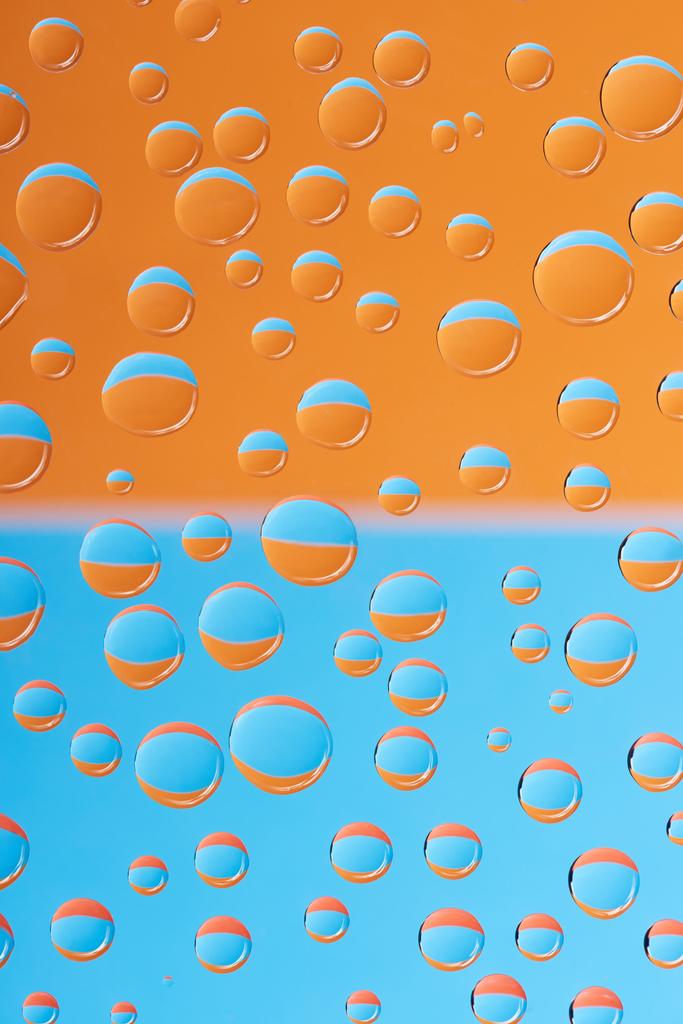 Vista de cerca de gotas de agua transparentes sobre fondo azul y naranja
 - Foto, imagen