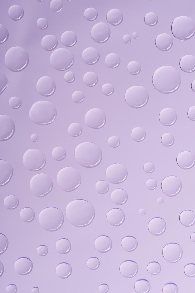 vergrote weergave van transparant water druppels op violette achtergrond - Foto, afbeelding