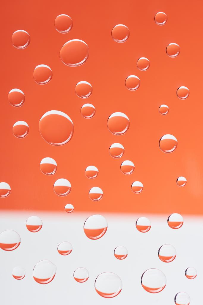 lähikuva läpinäkyvistä rauhallisista pisaroista valkoisella ja oranssilla taustalla
         - Valokuva, kuva