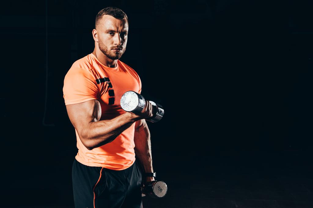 apuesto deportista en forma haciendo ejercicio con las barras en el gimnasio oscuro
 - Foto, Imagen