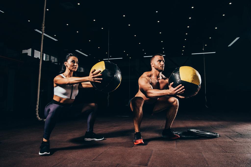 deportista atlético y deportista haciendo ejercicio con bolas de medicina juntos en el gimnasio oscuro
 - Foto, imagen