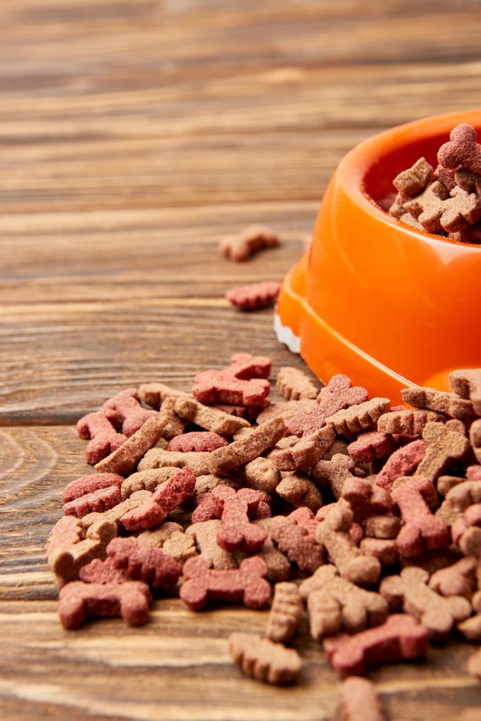 selective focus of plastic bowl with pile of pet food on wooden table - Photo, Image