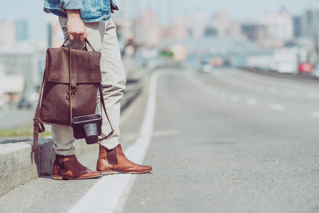 vista parcial do turista com mochila em pé na estrada
 - Foto, Imagem
