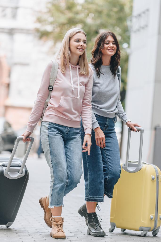 женщины-туристы с рюкзаками и багажом ходьба по улице города
 - Фото, изображение
