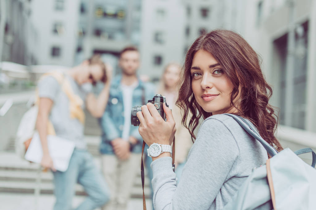 приваблива брюнетка дівчина з фотоапаратом, що йде в місті з друзями
 - Фото, зображення