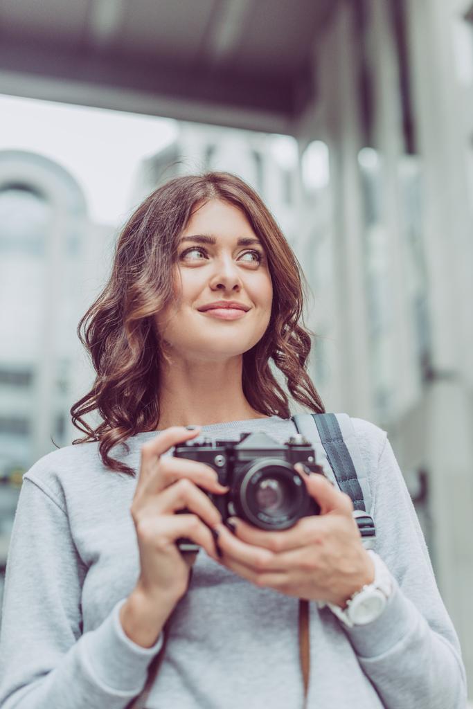 attractive brunette woman with photo camera in city - Photo, Image