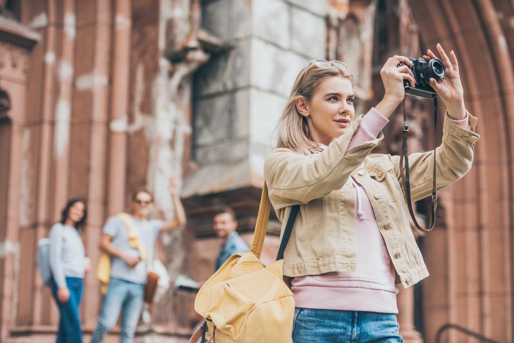 attractive girl taking photo of city on camera with friends behind - Photo, Image
