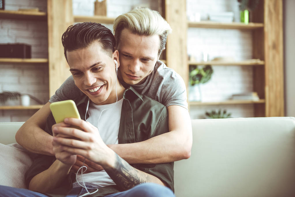 felice gay coppia coccole e guardando video su smartphone
 - Foto, immagini