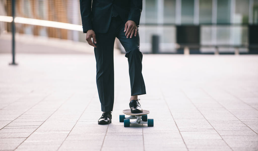 Homem bonito jovem com terno de negócios montando em um longboard - retrato empresário corporativo, conceitos sobre negócios, mobilidade e estilo de vida
 - Foto, Imagem