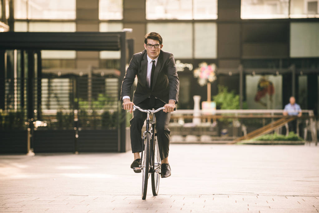 Joven hombre guapo con traje de negocios bicicleta de conducción - Retrato de hombre de negocios corporativo, conceptos sobre negocios, movilidad y estilo de vida
 - Foto, Imagen