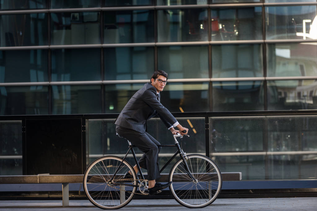 Young handsome man with business suit driving bycicle - Corporate businessman portrait, concepts about business, mobility and lifestyle - Photo, Image