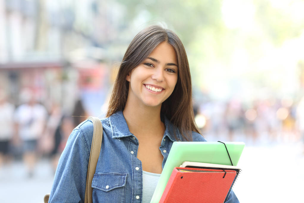 Szczęśliwy student posiadający folderów stanowi, patrząc na kamery na ulicy - Zdjęcie, obraz