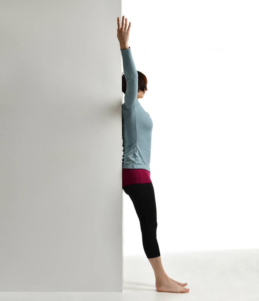 Cvičení v šestinedělí dělat žena. Ženského fitness instruktor protahování páteře u zdi v tělocvičně zacvičit cvičení - Fotografie, Obrázek