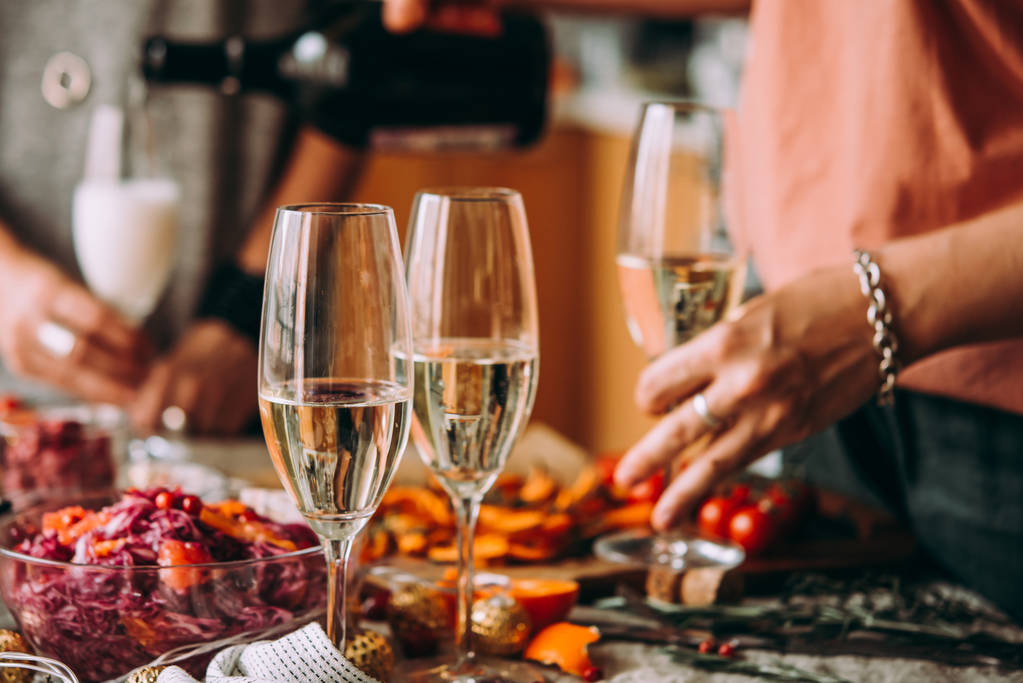 Champagner einschenken bei einer Dinnerparty mit Freunden. Tisch essen, Weihnachten oder Silvester feiern. - Foto, Bild