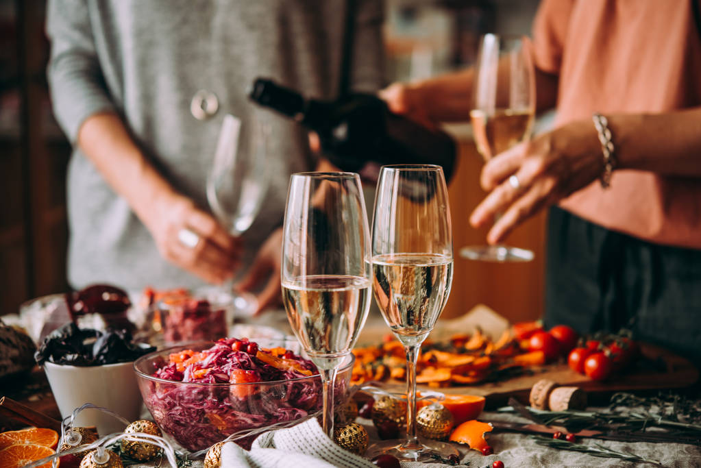Szakadó champagne: egy vacsora a barátokkal. Ebédlőasztal, ünneplő karácsony vagy újév előestéjén. - Fotó, kép