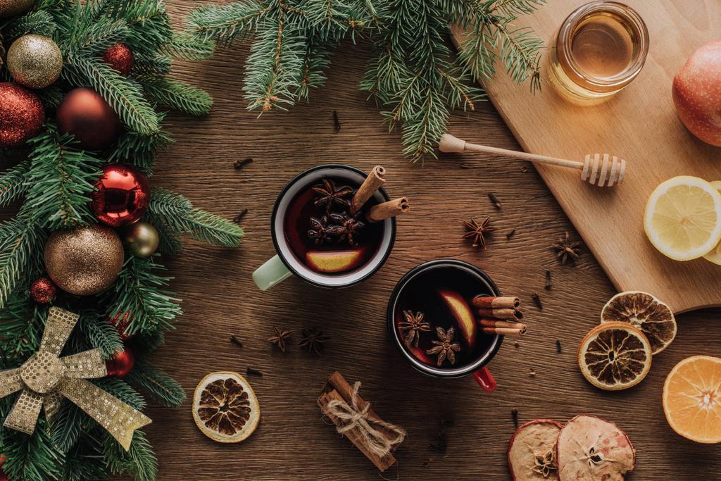 bovenaanzicht van kopjes glühwein en Spar twijgen met kerstballen op houten tafelblad, Kerstmis concept - Foto, afbeelding
