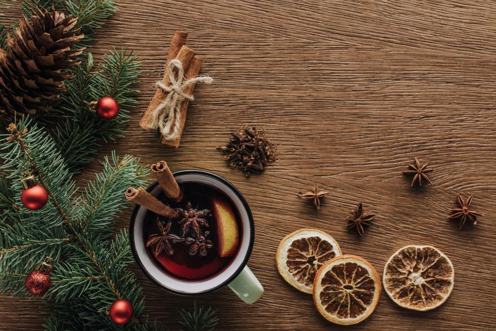 bovenaanzicht van glühwein, gedroogde sinaasappelen en Spar twijgen met kerstballen op houten tafelblad, Kerstmis concept - Foto, afbeelding