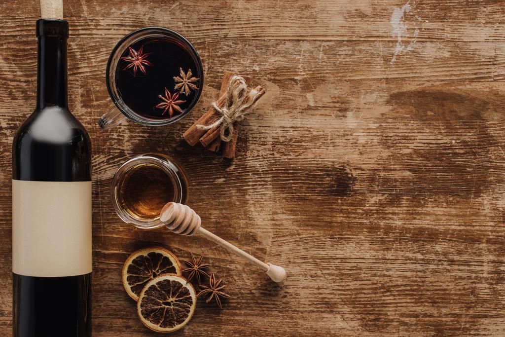 verhoogde weergave van glühwein, honing en wijn fles in houten tafel - Foto, afbeelding