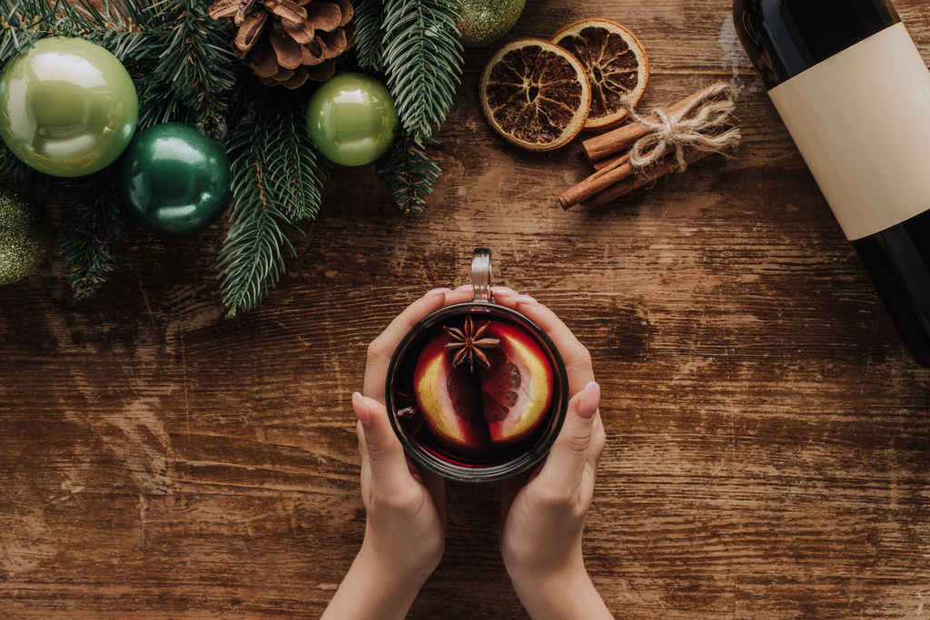 cropped image of woman holding glass of mulled wine at wooden tabletop, christmas concept - Photo, Image