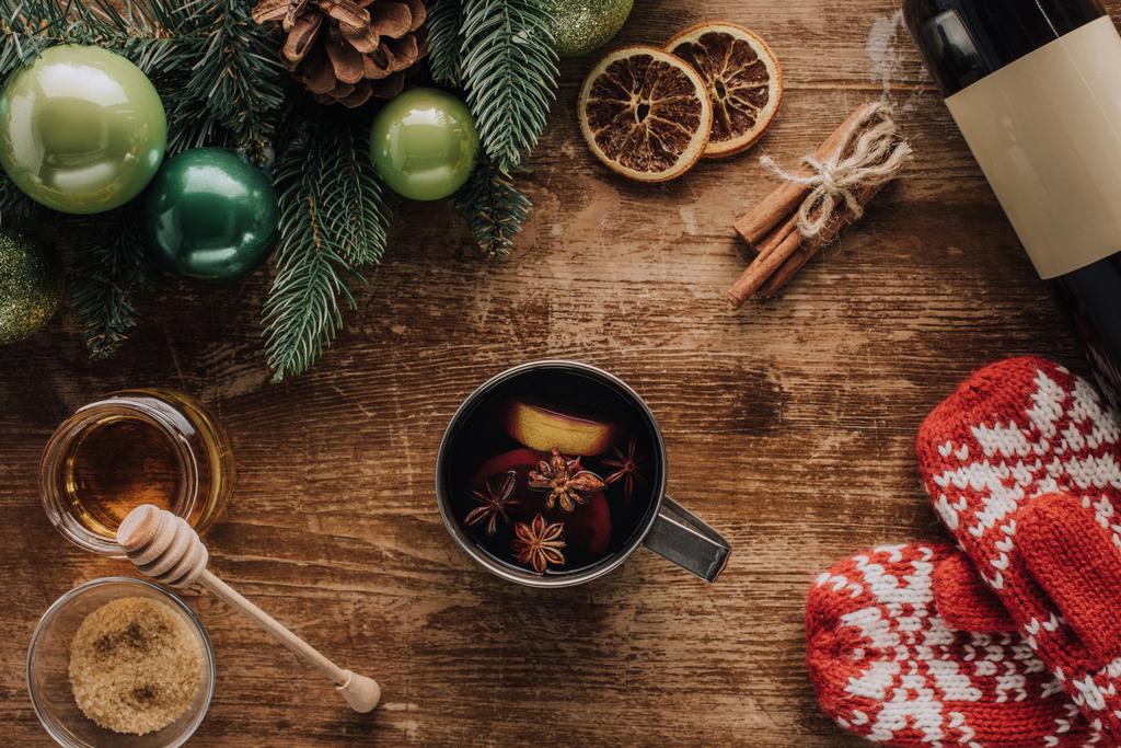 vista elevada de xícara de vinho ruminado e mitenes de inverno na mesa de madeira, conceito de Natal
 - Foto, Imagem