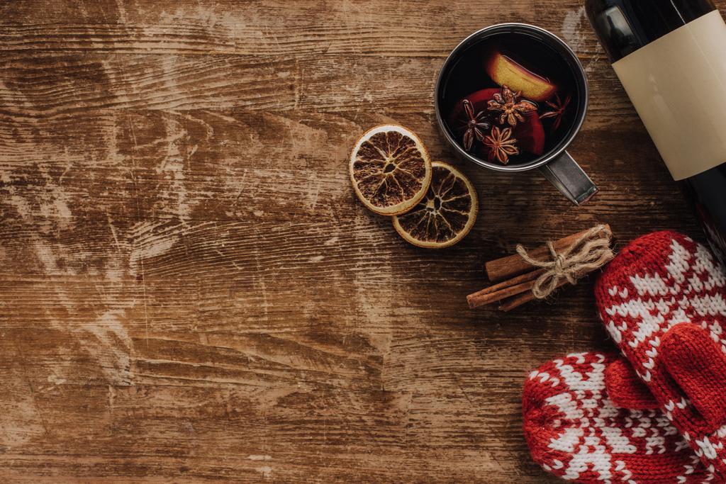 Widok z góry grzanego wina w butelce cup, rękawiczki i wina na drewnianym stole, koncepcja Boże Narodzenie - Zdjęcie, obraz