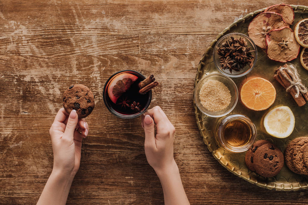 oříznutý obraz ženy držící šálek svařeného vína a cookie na dřevěný stůl - Fotografie, Obrázek