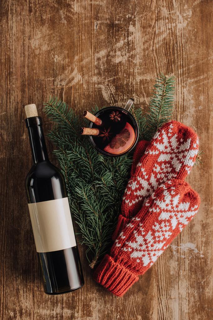 κάτοψη του μπουκάλι κρασί, mulled κρασί, Χριστουγεννιάτικο έλατο φλιτζάνι κλαδιά και γάντια για ξύλινα επιτραπέζια - Φωτογραφία, εικόνα