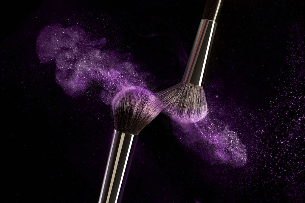 Make-up brush concept with ultraviolet, blue and orange powder explosion isolated on black background. Professional brush, powder trend color, place for text - Photo, Image