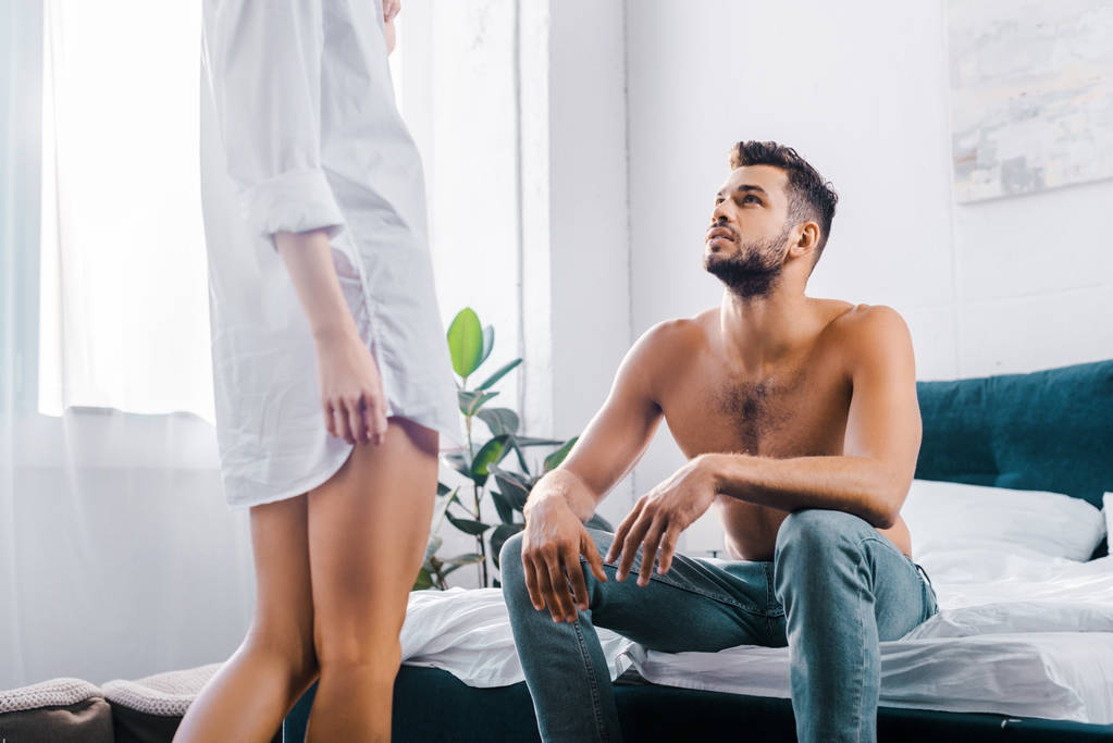 ritagliato colpo di donna in camicia in piedi davanti al suo fidanzato mentre lui seduto sul letto
 - Foto, immagini
