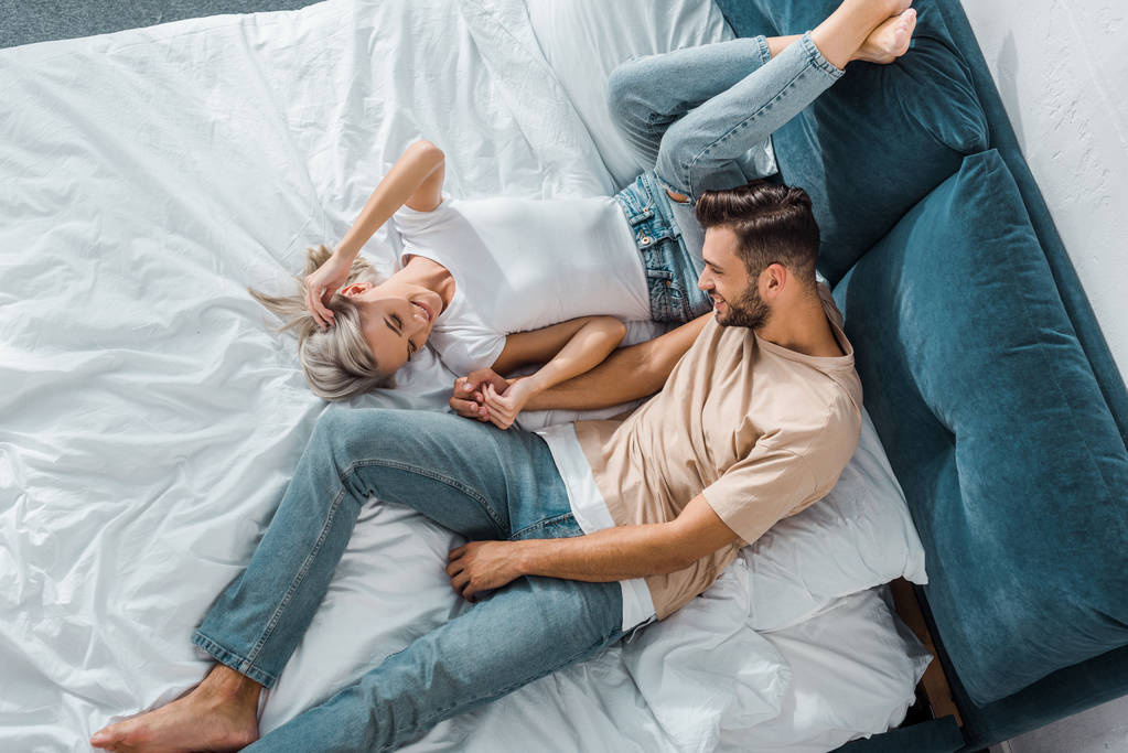 vista de ángulo alto de pareja joven atractiva relajarse juntos en el dormitorio
 - Foto, imagen